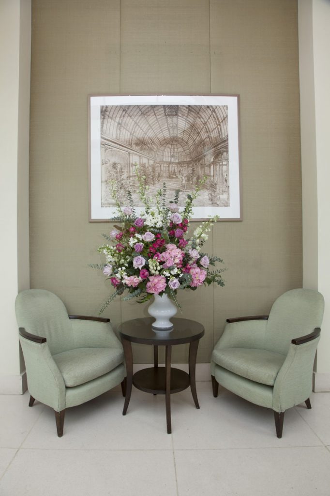 An airy pink, purple and white floral arrangement displayed between two chairs