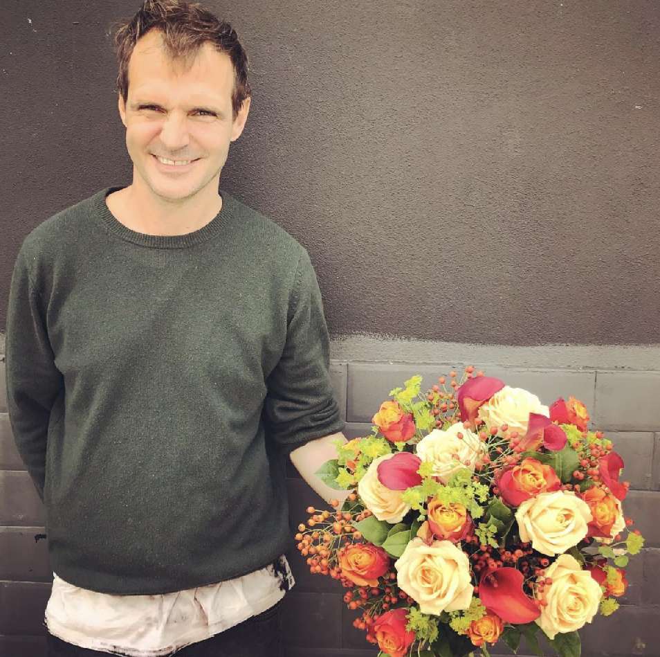David holding a hand-tied bouquet of yellow and red roses