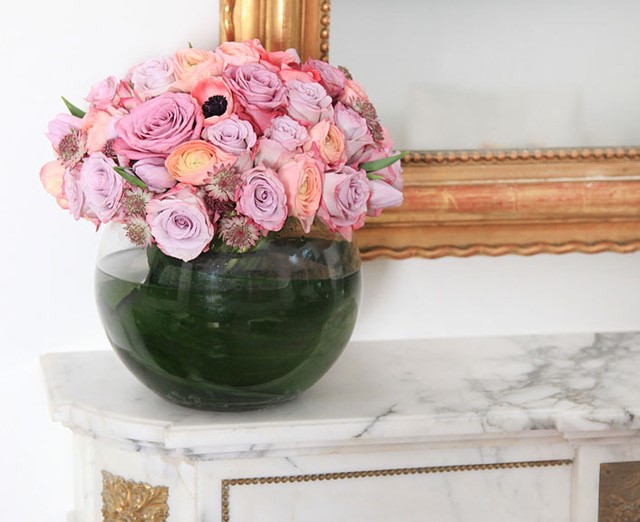 Pink roses and ranunculus arranged in a round glass vase
