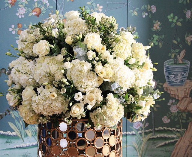 White roses and hydrangeas in a decorative gold vase